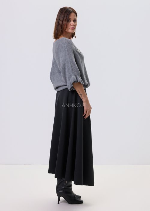 Szary sweter damski oversize z dekoracyjną falbaną na rękawie, gładka dzianina i luźny fason, stylizacja z czarnymi spodniami.