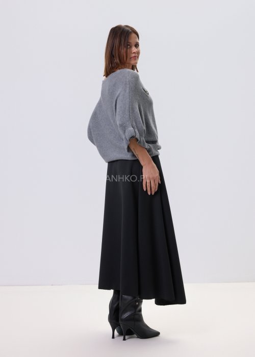 Szary sweter damski oversize z dekoracyjną falbaną na rękawie, gładka dzianina i luźny fason, stylizacja z czarnymi spodniami.