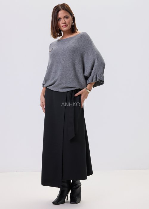 Szary sweter damski oversize z dekoracyjną falbaną na rękawie, gładka dzianina i luźny fason, stylizacja z czarnymi spodniami.