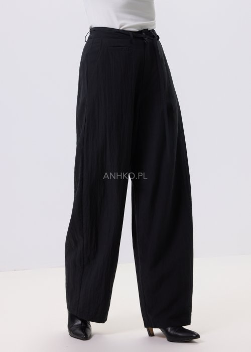 Czarne spodnie damskie z szeroką nogawką i wiązaniem w pasie, elegancki fason, stylizacja z białą bluzką i botkami.