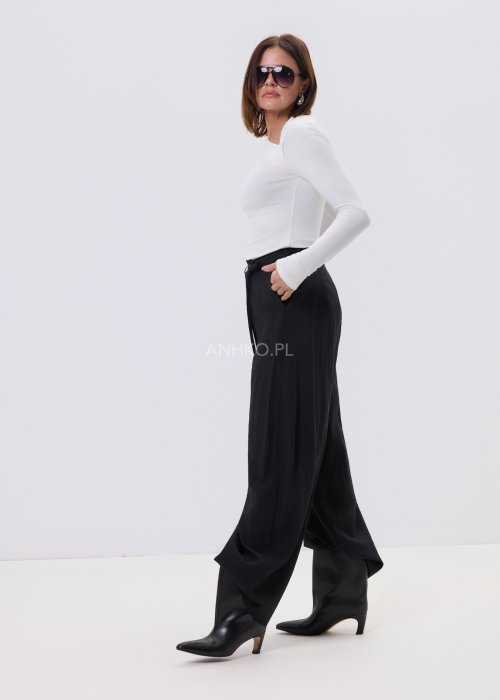 Czarne spodnie damskie z szeroką nogawką i wiązaniem w pasie, elegancki fason, stylizacja z białą bluzką i botkami.