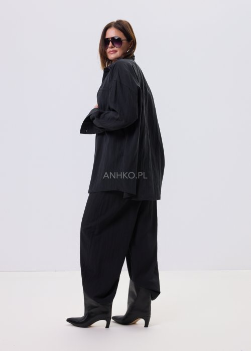 1Czarne spodnie damskie z szeroką nogawką i wiązaniem w pasie, elegancki fason, stylizacja z białą bluzką i botkami.