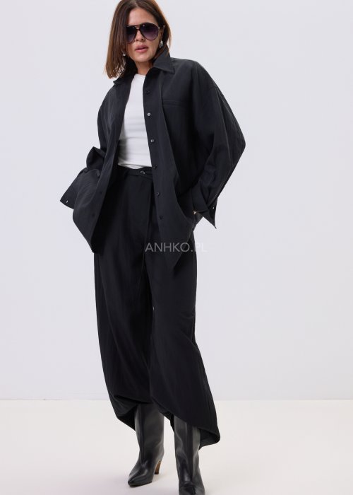 Czarne spodnie damskie z szeroką nogawką i wiązaniem w pasie, elegancki fason, stylizacja z białą bluzką i botkami.