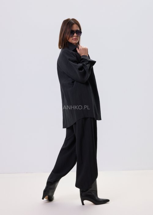 Czarne spodnie damskie z szeroką nogawką i wiązaniem w pasie, elegancki fason, stylizacja z białą bluzką i botkami.