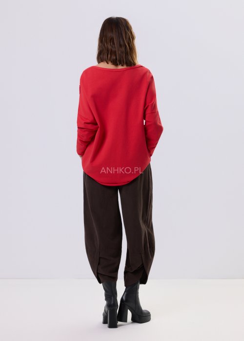 Brązowe spodnie sztruksowe o luźnym kroju z elastyczną talią i naszywanymi kieszeniami, zestawione ze sneakersami w casualowej, miejskiej stylizacji.