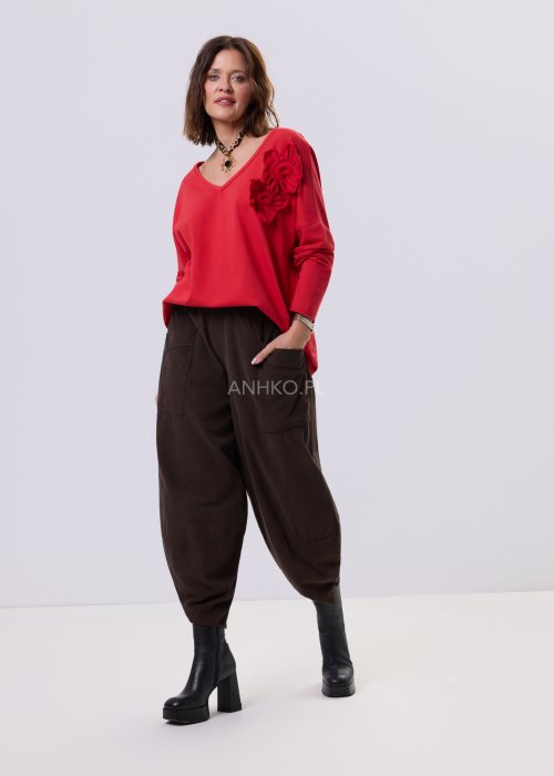 Brązowe spodnie sztruksowe o luźnym kroju z elastyczną talią i naszywanymi kieszeniami, zestawione ze sneakersami w casualowej, miejskiej stylizacji.