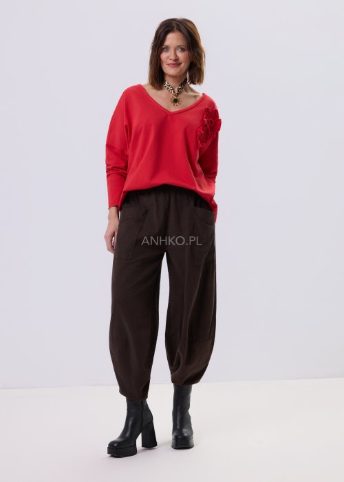 Brązowe spodnie sztruksowe o luźnym kroju z elastyczną talią i naszywanymi kieszeniami, zestawione ze sneakersami w casualowej, miejskiej stylizacji.