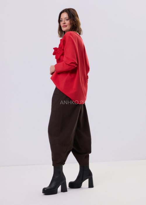 Brązowe spodnie sztruksowe o luźnym kroju z elastyczną talią i naszywanymi kieszeniami, zestawione ze sneakersami w casualowej, miejskiej stylizacji.