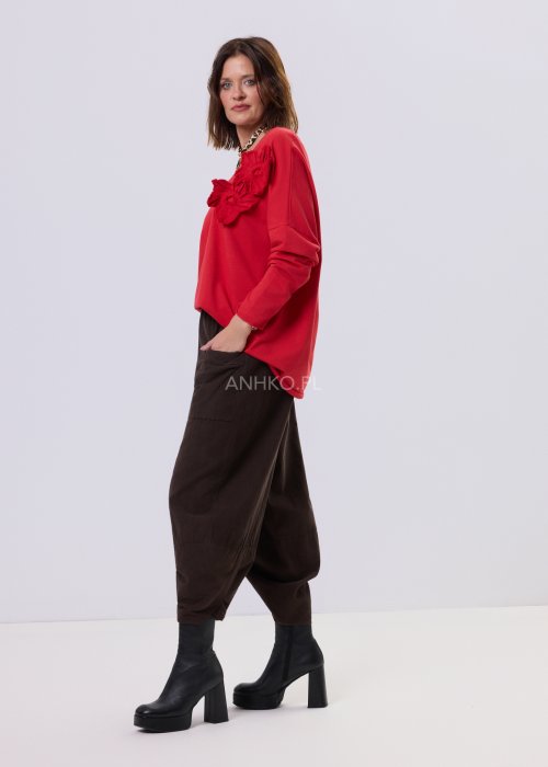 Brązowe spodnie sztruksowe o luźnym kroju z elastyczną talią i naszywanymi kieszeniami, zestawione ze sneakersami w casualowej, miejskiej stylizacji.