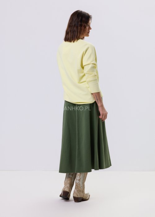 Żółta bluzka damska o luźnym kroju z haftem „Los Angeles” na przodzie, zestawiona z zieloną spódnicą w casualowej, miejskiej stylizacji.