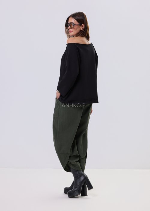 Czarna bluza damska o kroju oversize z raglanowymi rękawami, zestawiona z oliwkowymi spodniami i botkami w minimalistycznej, miejskiej stylizacji.