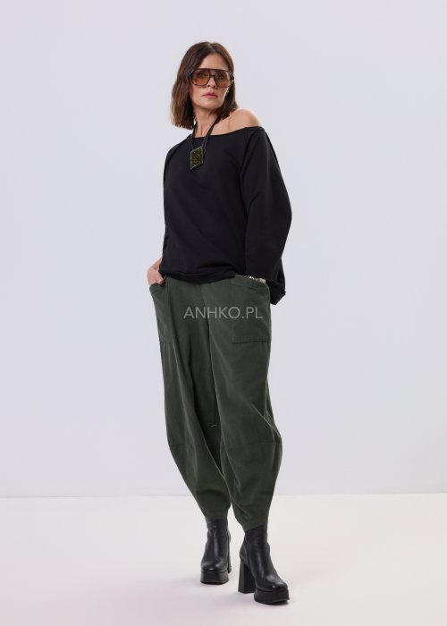 Czarna bluza damska o kroju oversize z raglanowymi rękawami, zestawiona z oliwkowymi spodniami i botkami w minimalistycznej, miejskiej stylizacji.