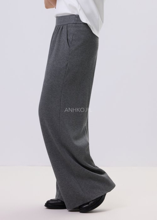 Szary komplet dzianinowy damski z luźnym kardiganem i szerokimi spodniami z wysokim stanem. Stylizacja z białym topem i czarnymi butami w minimalistycznym wydaniu.