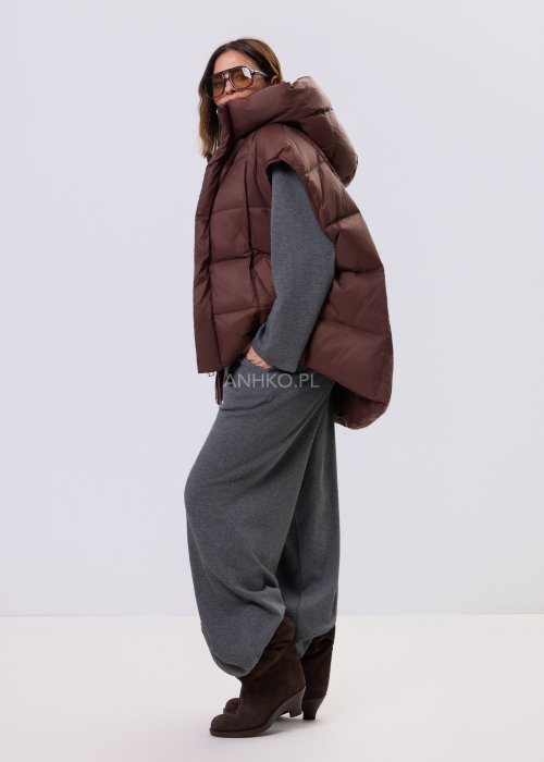 Brązowa kamizelka puchowa z kapturem i pikowaniem, zestawiona z szarym kompletem dresowym w miejskiej, casualowej stylizacji.