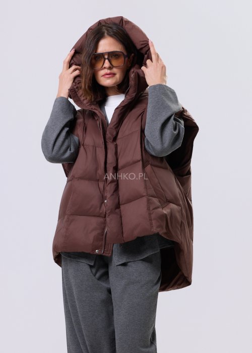 Brązowa kamizelka puchowa z kapturem i pikowaniem, zestawiona z szarym kompletem dresowym w miejskiej, casualowej stylizacji.