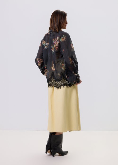 Czarna bluzka Liora Bloom w kwiaty z koronkowym wykończeniem, luźny fason, wiązanie przy szyi i długie rękawy, styl boho elegancki.