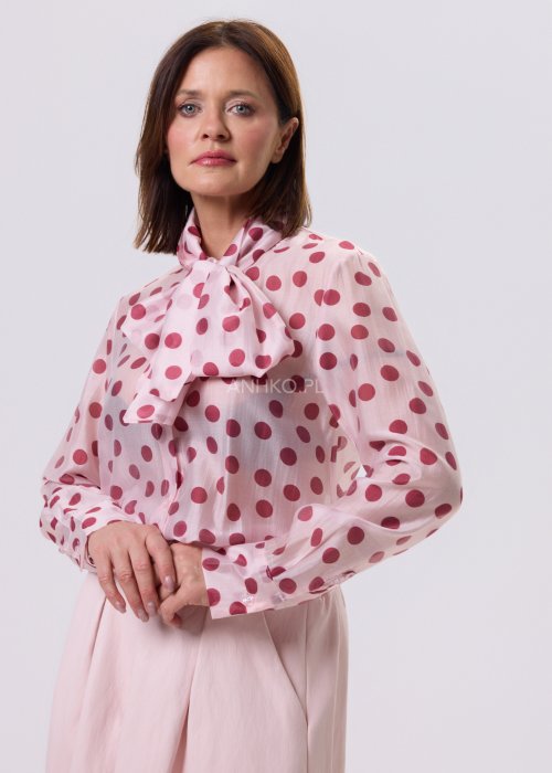 Jasnoróżowa bluzka Cherry Dot w wiśniowe groszki z wiązaną kokardą pod szyją, zapinana na guziki, lekki romantyczny fason.