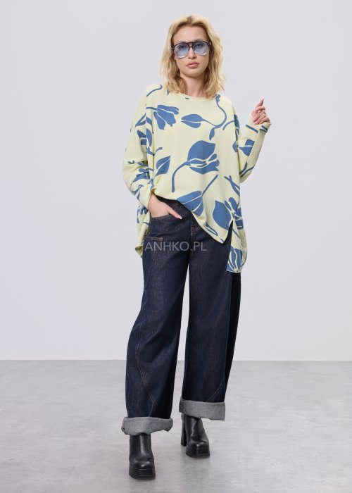 Żółta bluza damska oversize z niebieskim, graficznym wzorem roślinnym, luźny fason w stylizacji z ciemnymi jeansami.