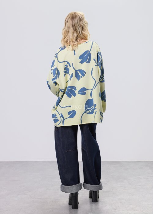 Żółta bluza damska oversize z niebieskim, graficznym wzorem roślinnym, luźny fason w stylizacji z ciemnymi jeansami.