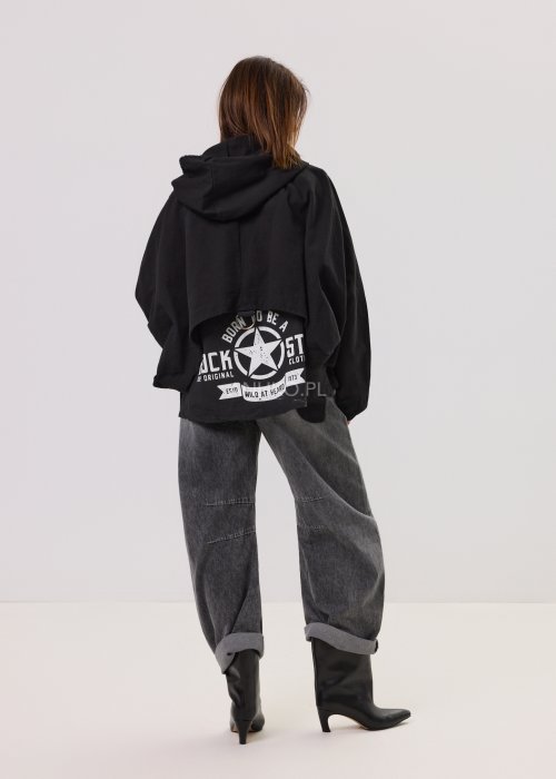 Czarna kurtka damska oversize z kapturem i zamkiem, zestawiona z jeansami z motywem serc w stylu streetwear.