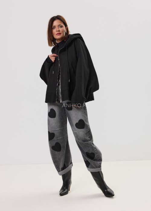 Czarna kurtka damska oversize z kapturem i zamkiem, zestawiona z jeansami z motywem serc w stylu streetwear.