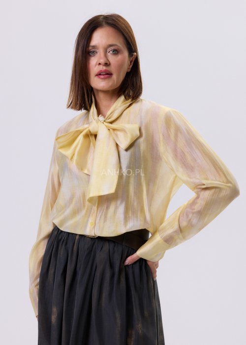 Masełkowa elegancka bluzka z wiązaną kokardą przy szyi i długim rękawem. Stylizacja z czarną spódnicą i paskiem podkreślającym talię.