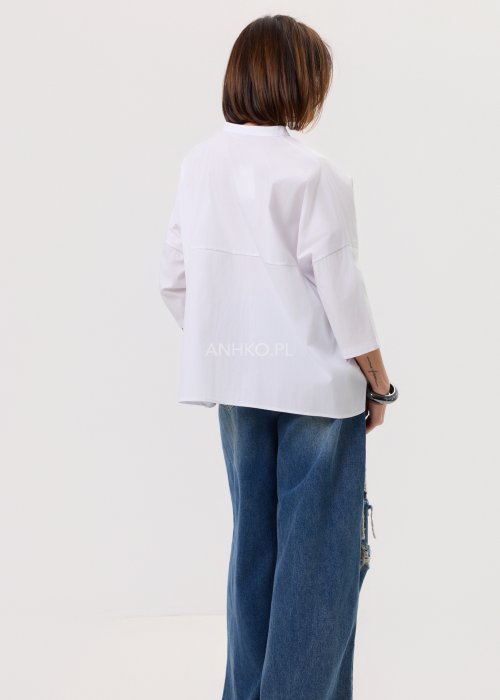 Damska biała koszula o luźnym kroju z obniżoną linią ramion, tył lekko wydłużony, zestawiona z denimem.
