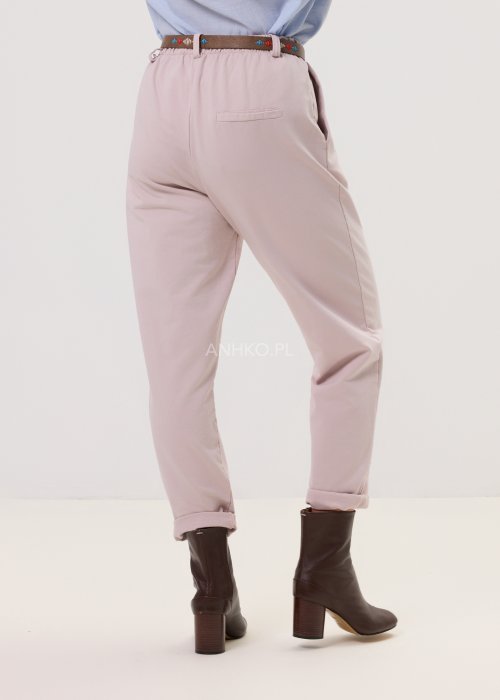 Pudrowe spodnie damskie chino o zwężanym kroju z podwijaną nogawką i paskiem, styl elegancki casual.