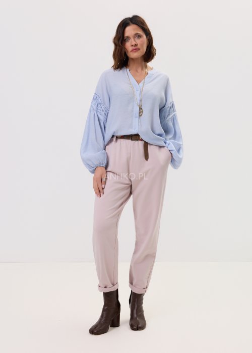 Pudrowe spodnie damskie chino o zwężanym kroju z podwijaną nogawką i paskiem, styl elegancki casual.