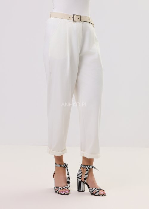 Białe spodnie Starola Rose z podwiniętą nogawką i eleganckim paskiem, luźny fason z zakładkami z przodu, w stylizacji z sandałami na słupku w czarno-białe paski.