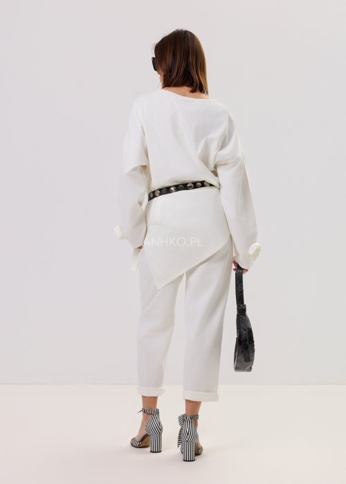 Białe spodnie Starola Rose z podwiniętą nogawką i eleganckim paskiem, luźny fason z zakładkami z przodu, w stylizacji z sandałami na słupku w czarno-białe paski.