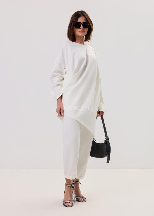 Białe spodnie Starola Rose z podwiniętą nogawką i eleganckim paskiem, luźny fason z zakładkami z przodu, w stylizacji z sandałami na słupku w czarno-białe paski.