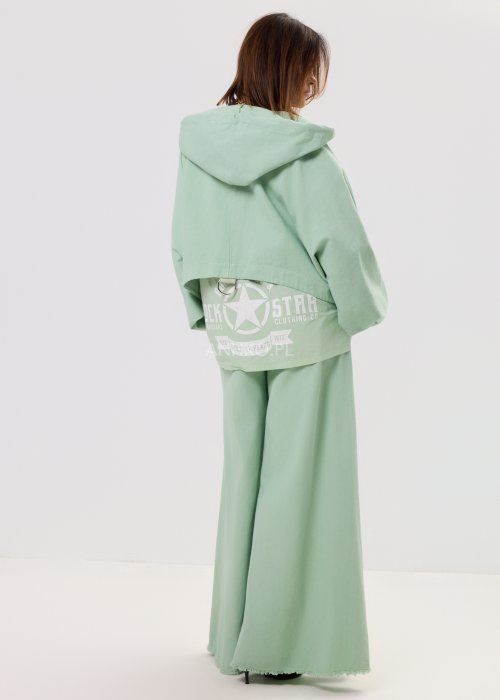 Kurtka damska oversize z kapturem, o krótszym kroju z tyłu z ozdobnym nadrukiem i metalowym kółkiem na plecach.