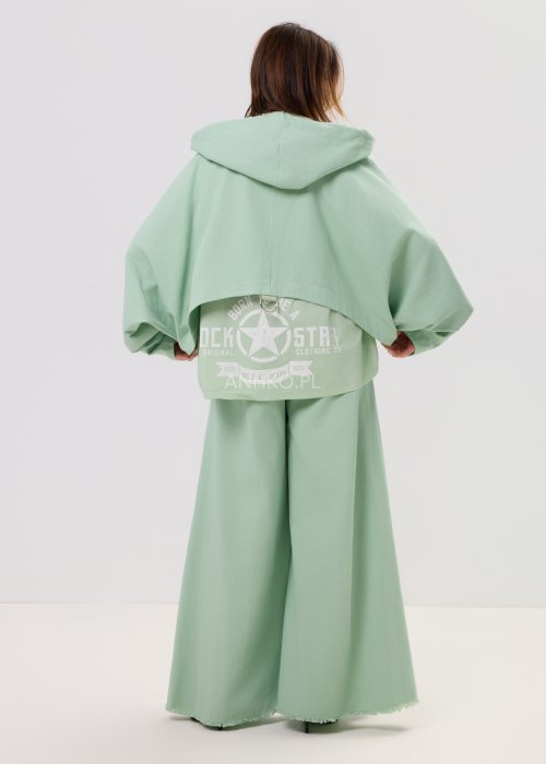 Kurtka damska oversize z kapturem, o krótszym kroju z tyłu z ozdobnym nadrukiem i metalowym kółkiem na plecach.