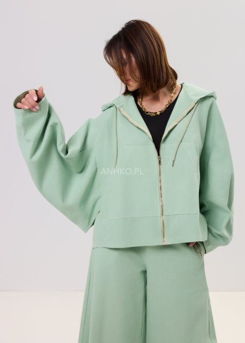 Kurtka damska oversize z kapturem, o krótszym kroju z tyłu z ozdobnym nadrukiem i metalowym kółkiem na plecach.