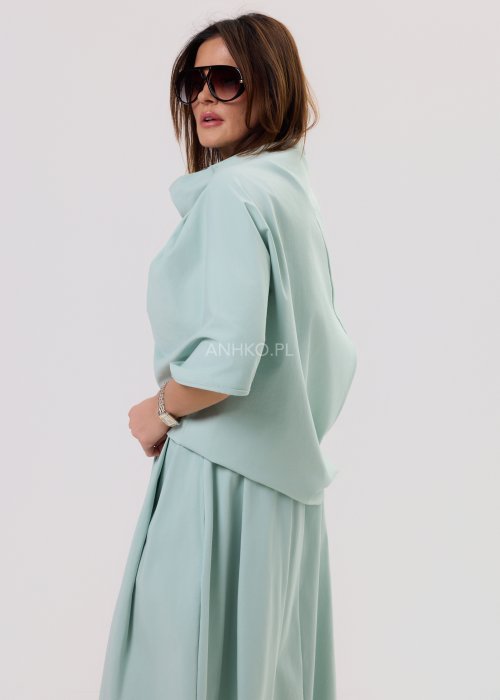 Miętowa damska bluzka o luźnym kroju z krótkim rękawem, szerokim dekoltem typu woda i dekoracyjnymi zakładkami z przodu.