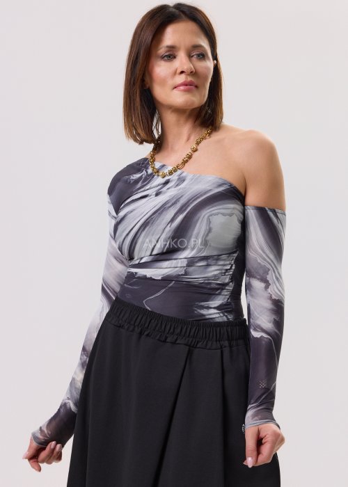 Bluzka dopasowana na jedno ramię z długim rękawem w marmurkowy wzór w odcieniach czerni, szarości i bieli. Nowoczesna stylizacja z czarną spódnicą w eleganckim, minimalistycznym stylu.