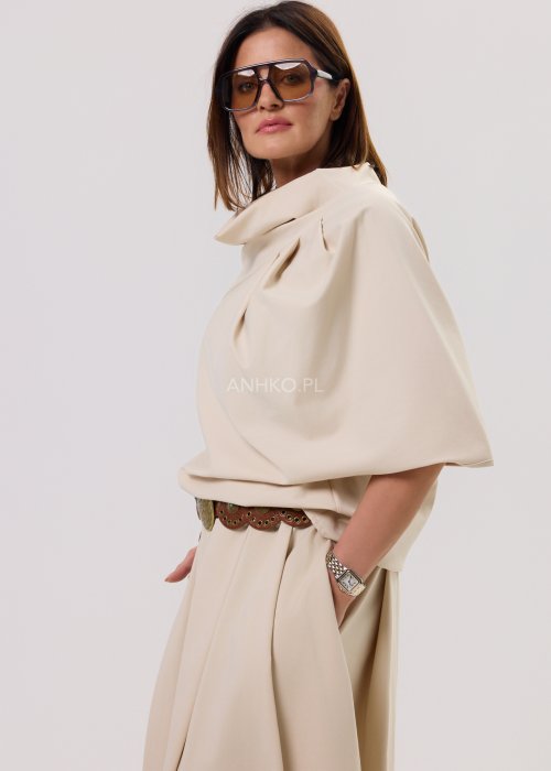 Beżowa damska bluzka o luźnym kroju z krótkim rękawem, szerokim dekoltem typu woda i dekoracyjnymi zakładkami z przodu.