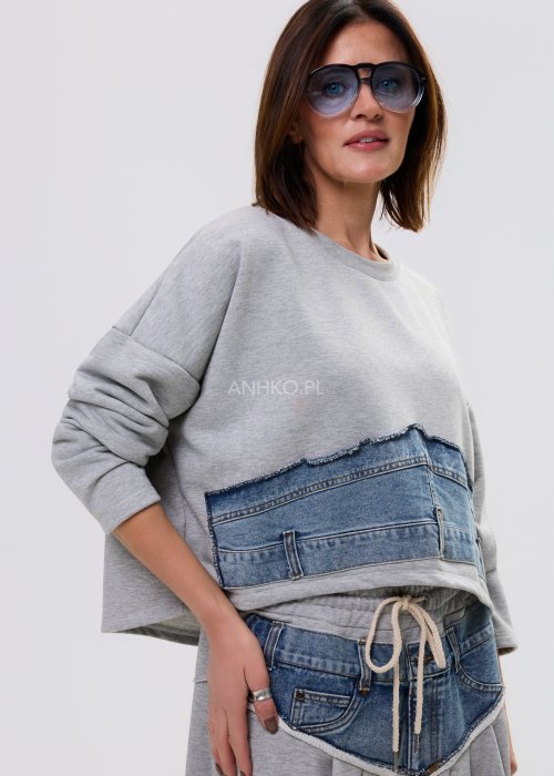 Szara damska bluza oversize z długim rękawem i zaokrąglonym dekoltem z dekoracyjną wstawką z denimu na przodzie.