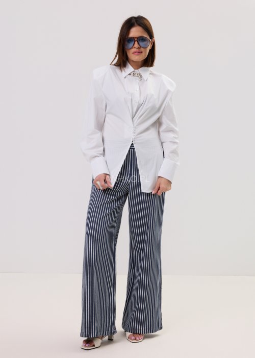 Biała koszula damska o klasycznym kroju z kołnierzykiem, zapinana na guziki, z długimi rękawami zakończonymi mankietami; delikatnie taliowana