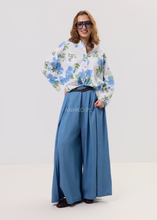 Biała koszula damska w niebieskie kwiaty z długim rękawem i luźnym krojem, zapinana na guziki, prezentowana w stylizacji casual.