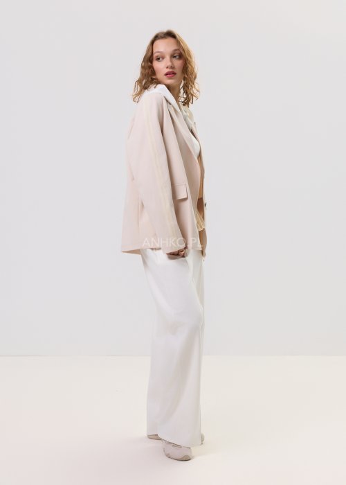 Beżowa marynarka damska z kapturem, zapinana na guziki, o luźnym kroju z kieszeniami, prezentowana w minimalistycznej stylizacji.