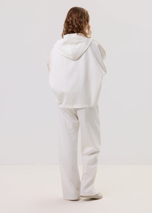 Damska kremowa bluza oversize z kapturem zapinana na zamek, szerokie rękawy, duża kieszeń z przodu – stylizacja z jasnymi spodniami.