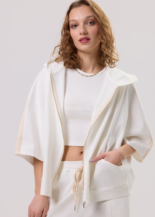 Damska kremowa bluza oversize z kapturem zapinana na zamek, szerokie rękawy, duża kieszeń z przodu – stylizacja z jasnymi spodniami.