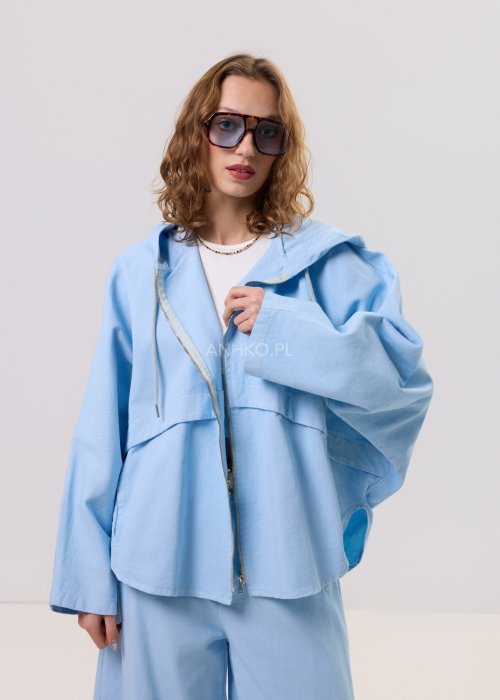 Niebieska kurtka damska z kapturem zapinana na zamek, o luźnym kroju z długim rękawem, prezentowana w stylizacji casual.