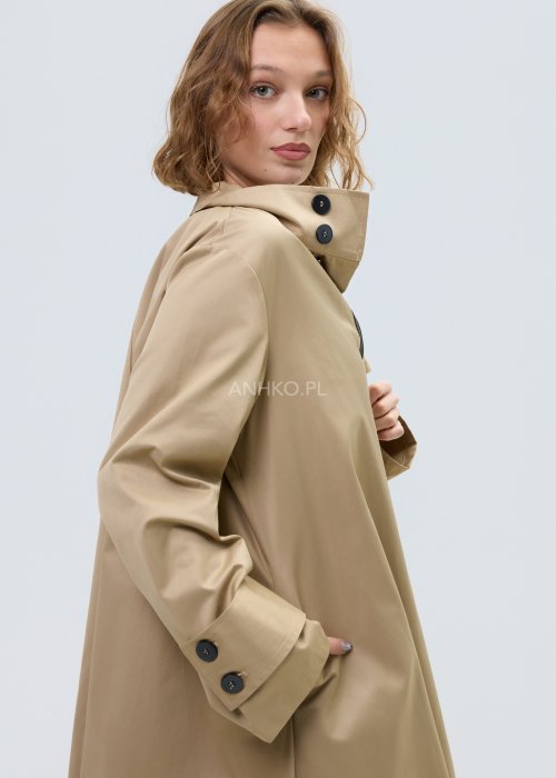 Beżowy płaszcz damski o luźnym, asymetrycznym kroju z wysokim kołnierzem. Model zapinany na zamek, z dekoracyjnymi guzikami przy kołnierzu i mankietach.