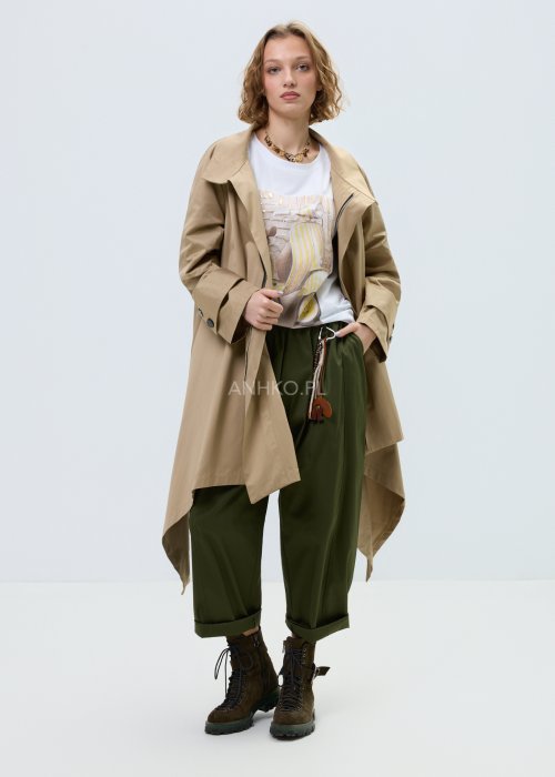 Beżowy płaszcz damski o luźnym, asymetrycznym kroju z wysokim kołnierzem. Model zapinany na zamek, z dekoracyjnymi guzikami przy kołnierzu i mankietach.