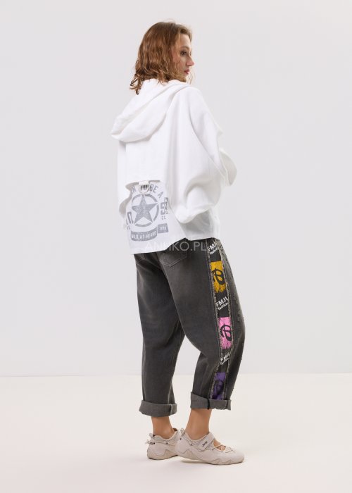 Damska biała bluza oversize z kapturem zapinana na zamek, duże kieszenie z przodu i nadruk z gwiazdą na plecach – casualowa stylizacja z jeansami.