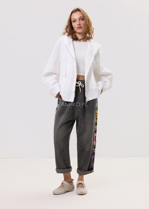 Damska biała bluza oversize z kapturem zapinana na zamek, duże kieszenie z przodu i nadruk z gwiazdą na plecach – casualowa stylizacja z jeansami.