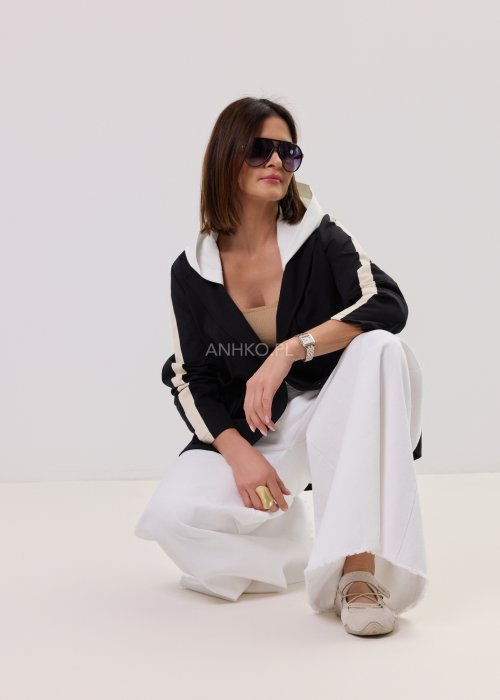 Czarna marynarka damska z kontrastowym kapturem i jasnymi lampasami na rękawach, o luźnym kroju, prezentowana w nowoczesnej stylizacji.